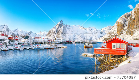 Fantastic winter view on Hamnoy village with port and Olstinden peak on background. Fantastic winter view on Hamnoy village with port and Olstinden peak on background. 73704087