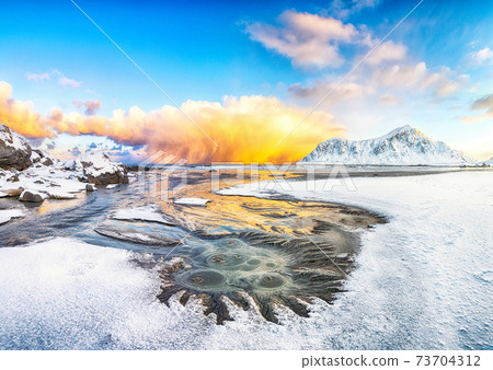 Incredible winter scenery on Skagsanden beach with illuminated clouds during sunrise. 73704312