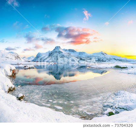 Fabulous frozen Flakstadpollen and Boosen fjords and reflection in water during sunrise with Hustinden mountain on background on Flakstadoya island 73704320