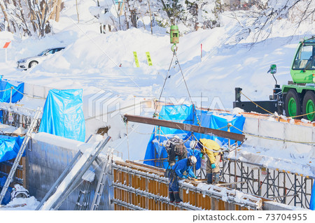 Lifting of materials by a crane car at a waterway construction site in winter 73704955
