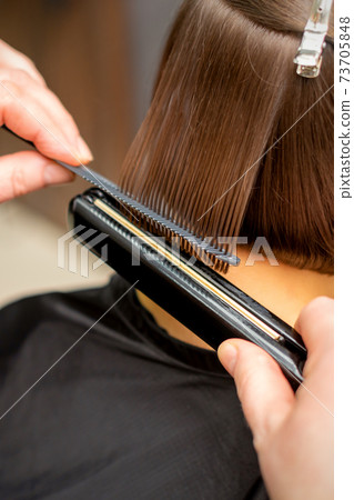 Hairdresser straightening the short hair 73705848