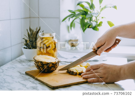 Fermented pineapple kombucha drink tepache. Cooking process of homemade probiotic superfood pineapple beverage. Drink jar and sliced pineapple on home kitchen 73706102