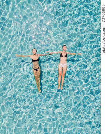 Couple of woman floating in transparent blue ocean. Aerial view Couple of woman floating in transparent blue ocean. Aerial view 73706996