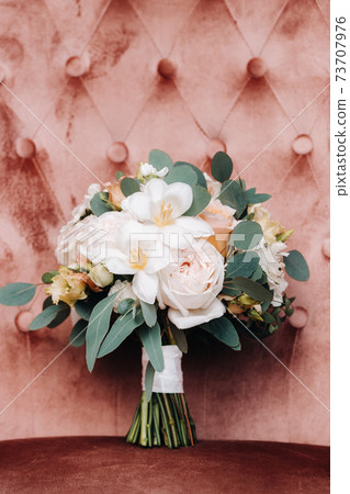 wedding bouquet with roses on the table and a boutonniere.The decor at the wedding 73707976