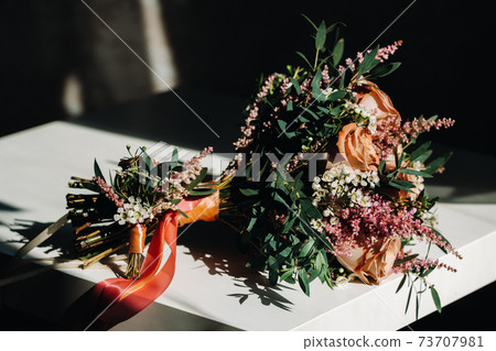 wedding bouquet with roses on the table and a boutonniere.The decor at the wedding 73707981