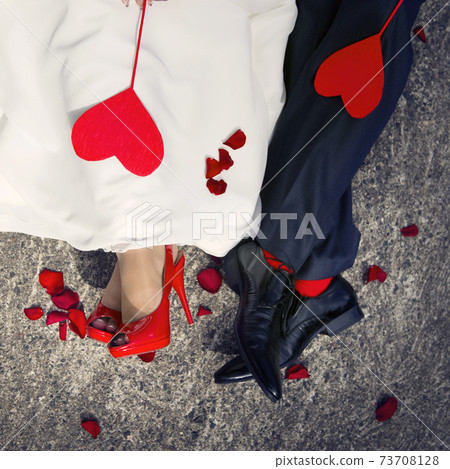 Close-up of lovers ' feet and two red hearts lying on them 73708128