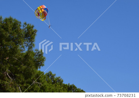 Parasailing in summer with colorful parachute, one persons in blue sky Parasailing in summer with colorful parachute, one persons in blue sky 73708231