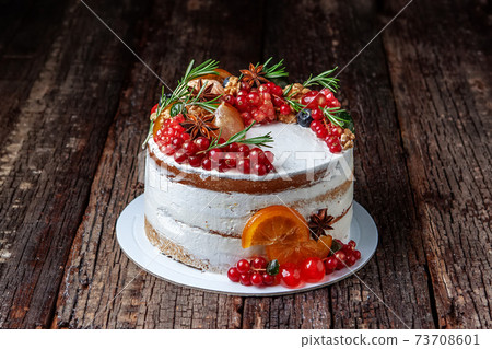 Tasty sweet cake decorated with fruit and rosemary, placed on old rustic table. 73708601
