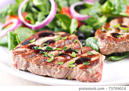 Fillet of beef with mixed salad on a plate. Fillet of beef with mixed salad on a plate. 73709018