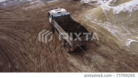 Dump truck Transports Soil On Construction Site. top view dump truck unloading soil sand construction site. big construction machine working Dump truck Transports Soil On Construction Site. top view dump truck unloading soil sand construction site. big construction machine working 73709208
