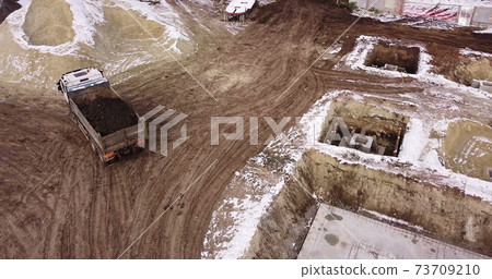 Dump truck Transports Soil On Construction Site. top view dump truck unloading soil sand construction site. big construction machine working Dump truck Transports Soil On Construction Site. top view dump truck unloading soil sand construction site. big construction machine working 73709210