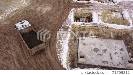 Dump truck Transports Soil On Construction Site. top view dump truck unloading soil sand construction site. big construction machine working Dump truck Transports Soil On Construction Site. top view dump truck unloading soil sand construction site. big construction machine working 73709211