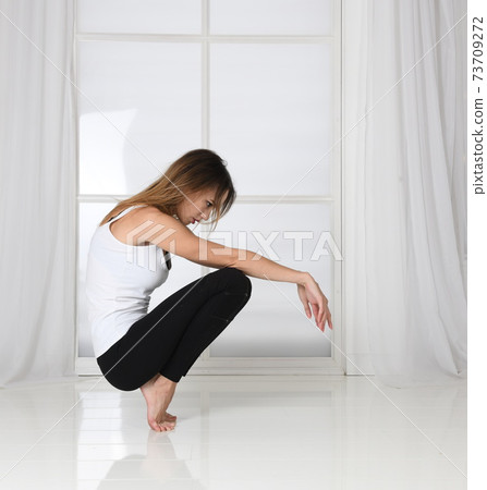The woman squats, keeps her balance, fitness, fashion model posing 73709272