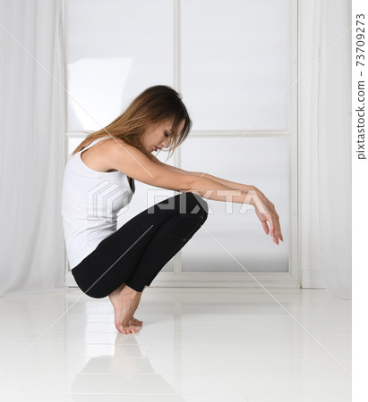 The woman squats, keeps her balance, fitness, posing, eyes closed 73709273