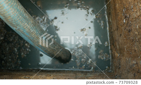 Cesspool septic emptying pumping into pipe tank by suction hose under high pressure. The sump contains pollution sludge sewage water black wastewater and faeces plus excrements from home 73709328