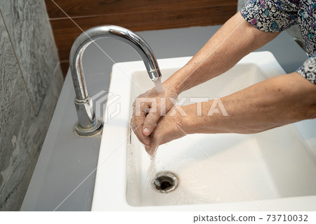 New Normal, Asian working woman washing hand by press blue alcohol sanitizer gel for protect safety infection and kill Covid-19 Coronavirus in office. 73710032