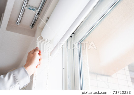 Hands of workers who install roll screens on windows 73710228