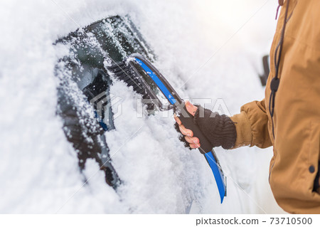 Man clear snow from car with cleaning tool 73710500