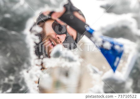 Man clear snow from car with cleaning tool Man clear snow from car with cleaning tool 73710522
