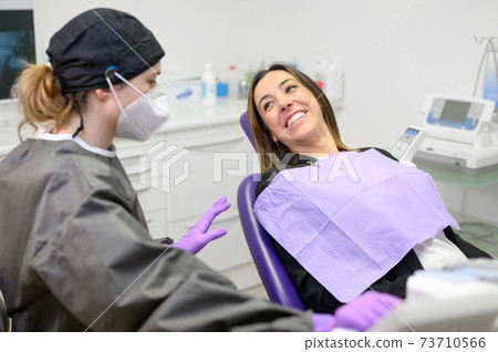 Young female patient visiting dentist office. Beautiful woman sitting at dental chair with open Young female patient visiting dentist office. Beautiful woman sitting at dental chair with open 73710566