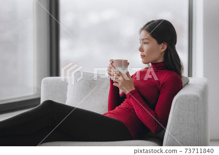 Happy Asian woman relaxing at home during coronavirus lockdown feeling calm and positive enjoying drinking coffee alone indoors. Mental health, wellness, well-being Happy Asian woman relaxing at home during coronavirus lockdown feeling calm and positive enjoying drinking coffee alone indoors. Mental health, wellness, well-being 73711840