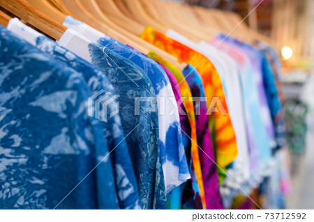 A rack of colorful shirts hanged for sale at local market. 73712592
