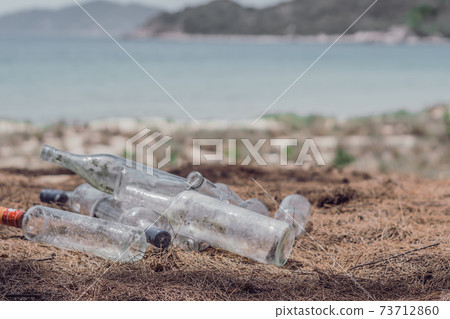 Close landfill old dirty transparent discarded empty glass alcohol drinks bottles trash on ground forest nature sea park. Alcoholism addiction problem bad habits, ecology issues environment pollution Close landfill old dirty transparent discarded empty glass alcohol drinks bottles trash on ground forest nature sea park. Alcoholism addiction problem bad habits, ecology issues environment pollution 73712860