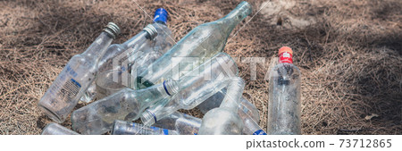 BANNER landfill old dirty transparent discarded empty glass alcohol drink bottles trash on ground forest nature sea park. Alcoholism addiction problem bad habits, ecology issues environment pollution 73712865