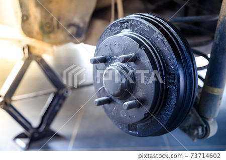 A rear hub of the car after removing a tire and wheel, maintaining a brake and wheel system, car jack-up for change a car wheel, Close-up shot A rear hub of the car after removing a tire and wheel, maintaining a brake and wheel system, car jack-up for change a car wheel, Close-up shot 73714602