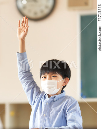Elementary school students in masks raising their hands 73715838