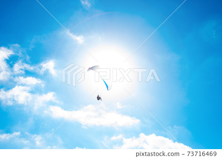 巴拉滑翔機和太陽在藍色夏日的天空中飛翔 巴拉滑翔機和太陽在藍色夏日的天空中飛翔 73716469