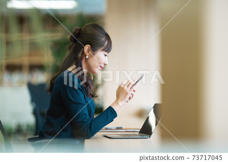 A woman looking at a smartphone in a coworking space 73717045