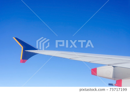 Aircraft wing view from airplane window seat. Beautiful blue sky with sunlight and cloud. Aircraft wing view from airplane window seat. Beautiful blue sky with sunlight and cloud. 73717199