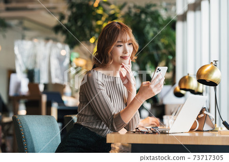 A woman watching a smartphone at a cafe A woman watching a smartphone at a cafe 73717305