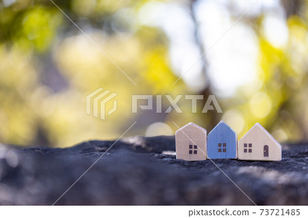 Three small wooden houses with sunbeams back Three small wooden houses with sunbeams back 73721485