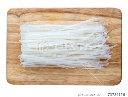 Rice noodles on a white background. Dry rice noodles on a wooden board carved on a white background. 73726156