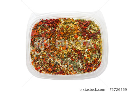 Dry seasoning in a plastic container. Different condiments in a container on a white background. Dry seasoning in a plastic container. Different condiments in a container on a white background. 73726569