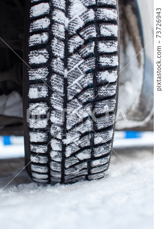 Car tires on the winter road are covered with snow. Car tires on the winter road are covered with snow. 73726943