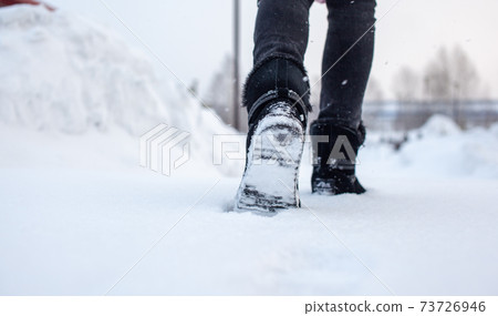 A person is walking on a slippery road, the first snow in the park A person is walking on a slippery road, the first snow in the park 73726946