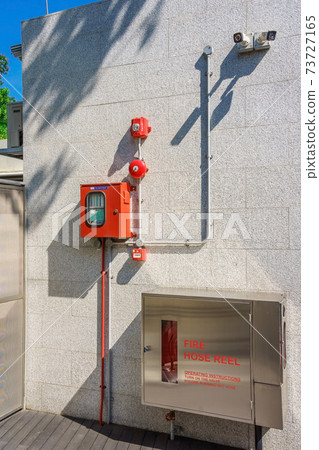 Water hose to extinguish the fire in cabinet and alarm system at brick wall. Fire equipment. Water hose to extinguish the fire in cabinet and alarm system at brick wall. Fire equipment. 73727165
