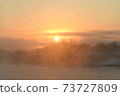The orange sun shines reflecting off the ice of the river in the winter morning. 73727809