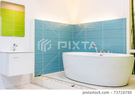 White and wooden bathroom corner with a white bathtub, a toilet and a built in shelf for self care products 73728780