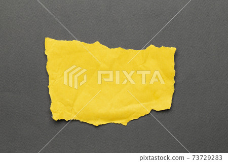 Torn real paper yellow color scraps on gray background Torn real paper yellow color scraps on gray background 73729283
