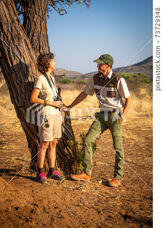 Guide stands talking to brunette by tree Guide stands talking to brunette by tree 73729348