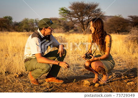Guide squatting in grassland makes brunette laugh Guide squatting in grassland makes brunette laugh 73729349