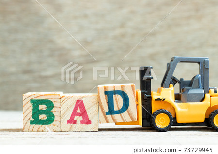Toy forklift hold letter block d to complete word bad on wood background Toy forklift hold letter block d to complete word bad on wood background 73729945