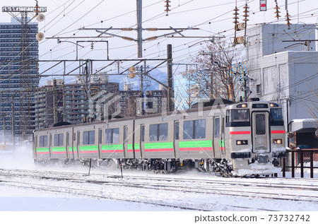 Regular train on the Hakodate Main Line heading to Ebetsu with snow smoke 73732742