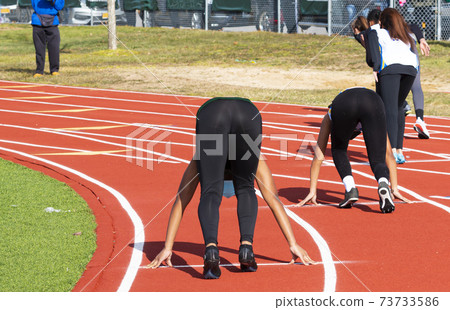 Rear view of high school girls starting a sprint running race 73733586