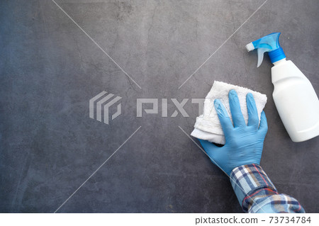 hand in blue rubber gloves cleaning table with cloth  73734784