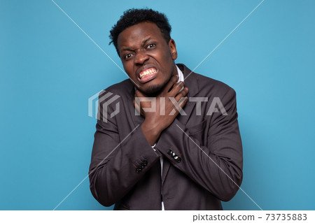 African man holding hands crossed on neck and chocking himself, feeling pain African man holding hands crossed on neck and chocking himself, feeling pain 73735883